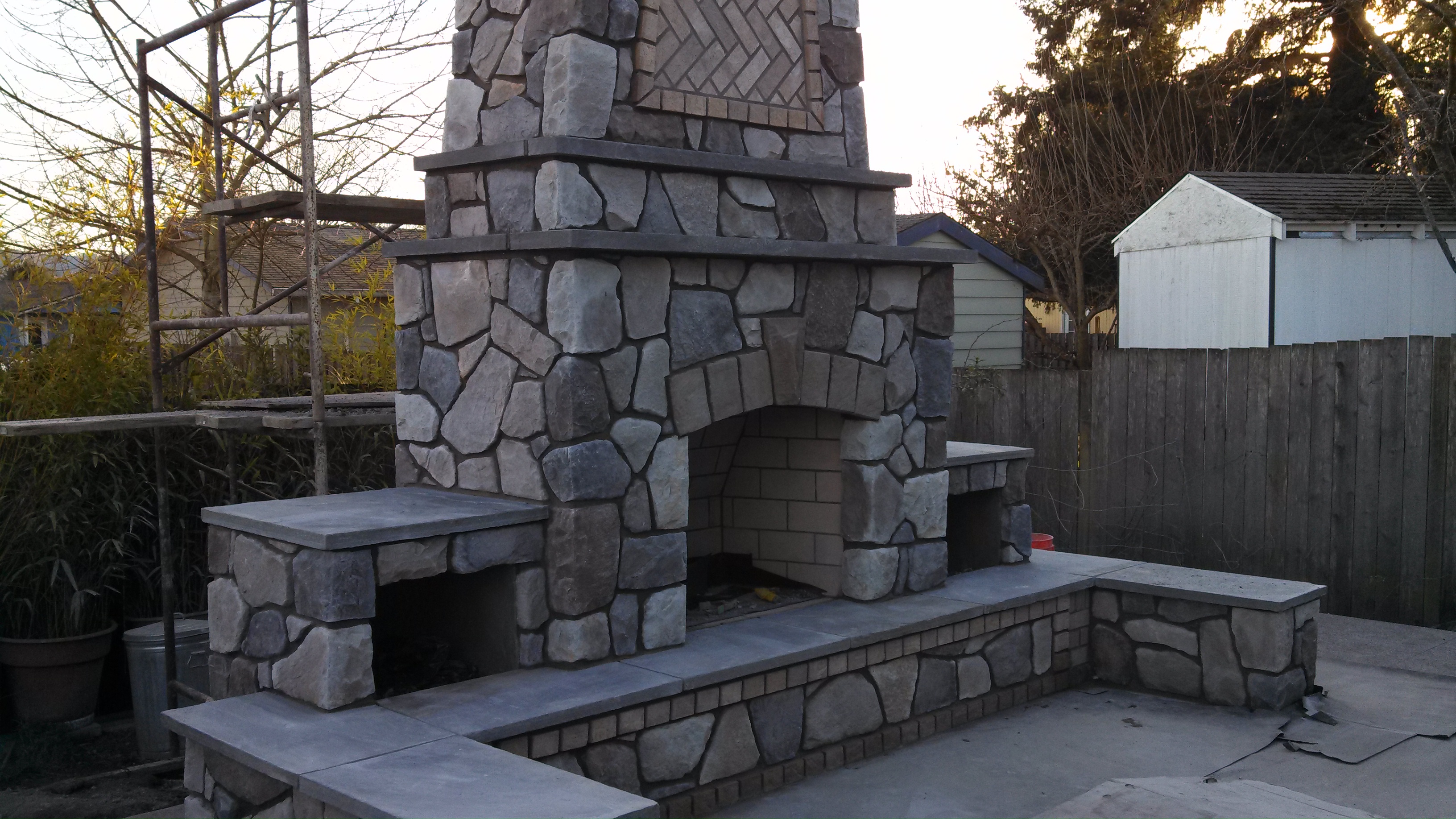 A large stone outdoor fireplace, featuring a tall chimney with a decorative pattern.